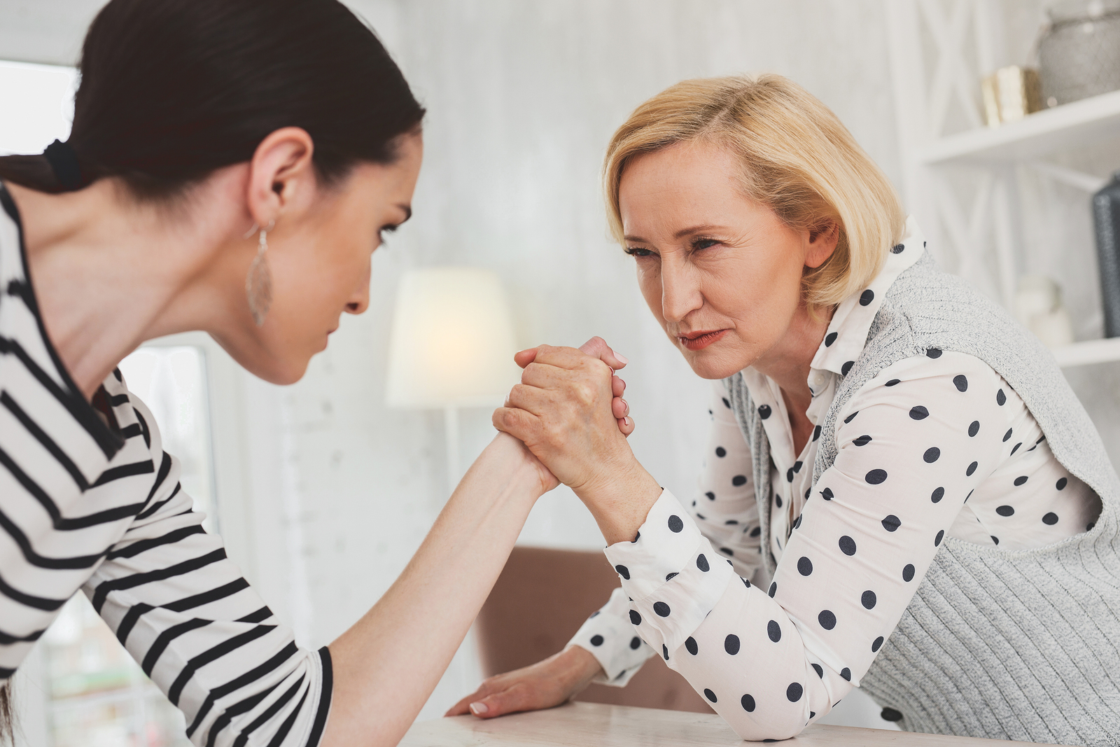 I will win. Serious concentrated woman looking at her daughter in law while holding her hand