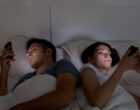 Young couple with smartphones in their bed