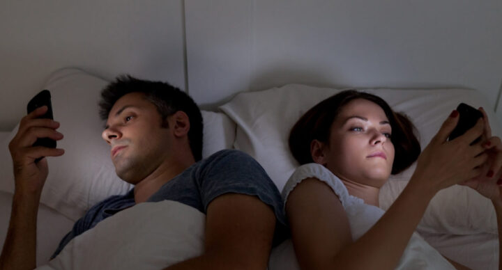 Young couple with smartphones in their bed