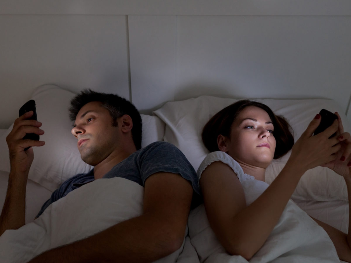 Young couple with smartphones in their bed